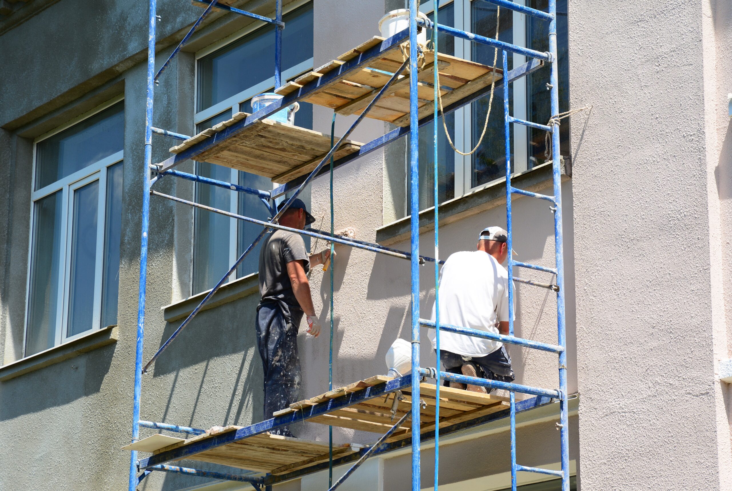 Painting stucco exterior walls. The building contractors are plastering and painting a stucco facade of a house.
